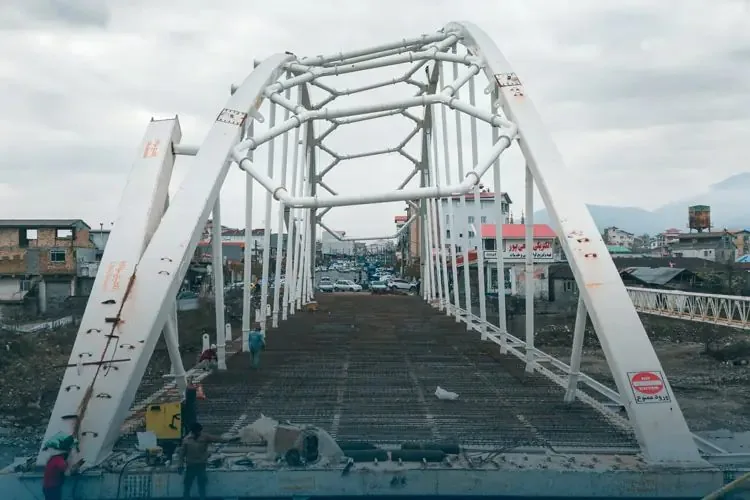 The white bolted steel arch of the Asalem bridge spanning the deck during construction
