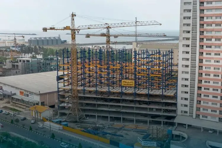 Tower cranes over the steel frame of the Tavoos residential towers beside the Caspian port